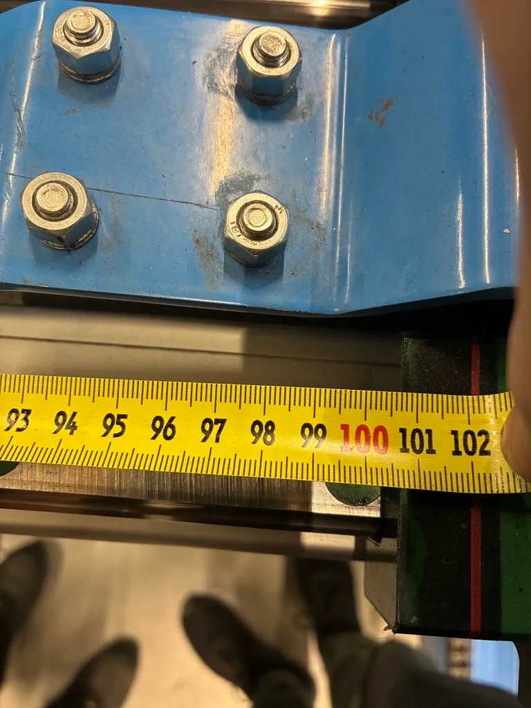 Vermessung an der Mechanik einer Laseranlage mit dem Massband zur Pruefung des Achsversatzes