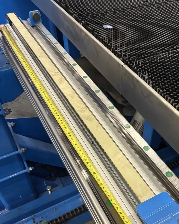 Linearführung und Zahnstange einer Achse, daneben ein ausgelegtes Maßband