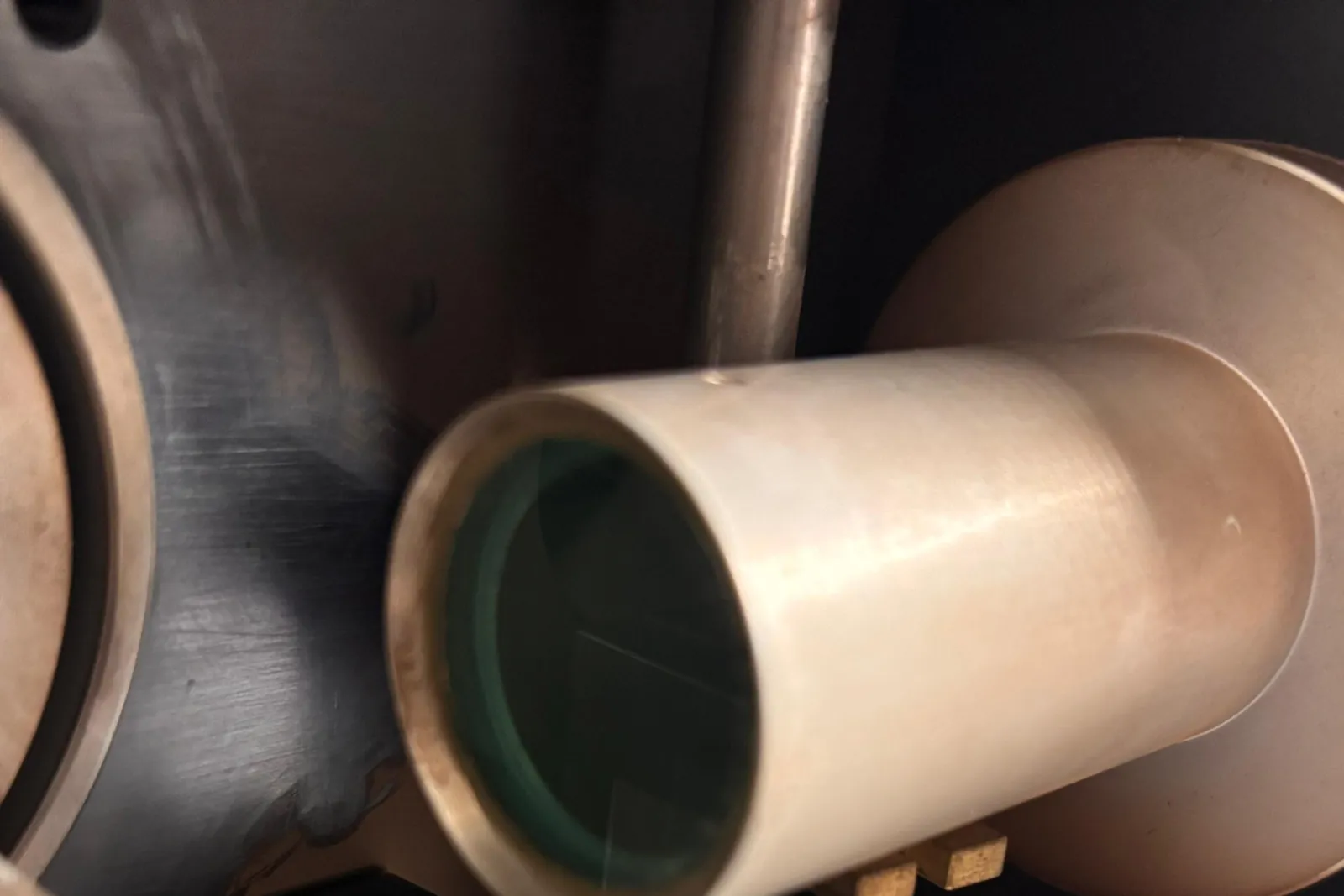 Metallisches Strahlrohr mit grünlich schimmerndem Schutzfenster im Laserkopf