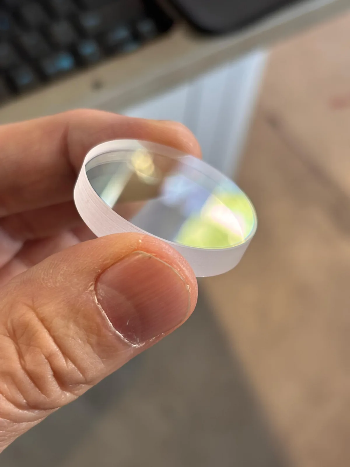 Runde Laserlinse in einer Hand, gegen das Licht gehalten