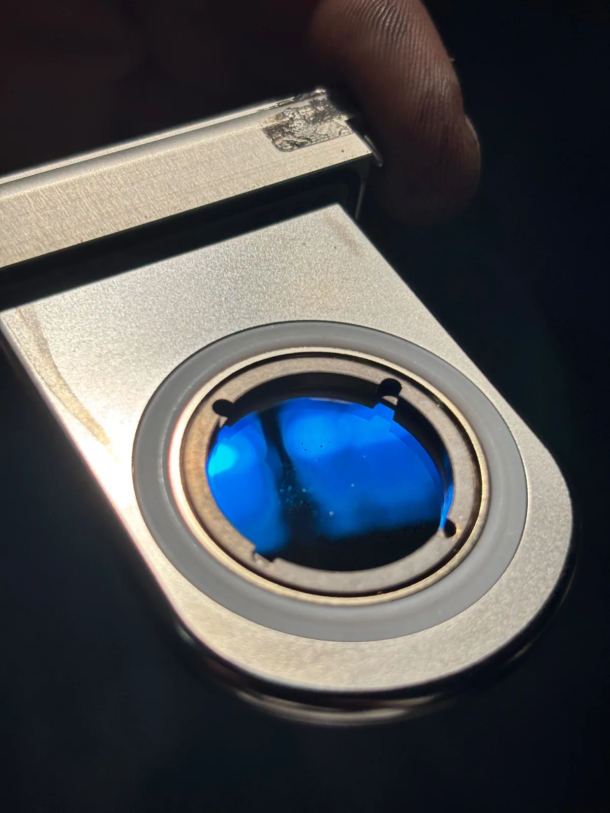 Runde Laseroptik in einer Metallfassung mit tiefblau schillernder Beschichtung